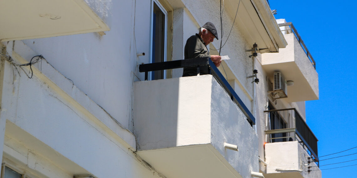 idős férfi az erkélyen újságot olvas