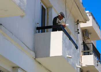 idős férfi az erkélyen újságot olvas