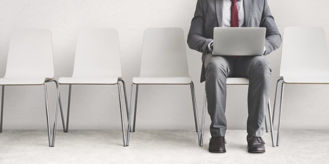 állásinterjúra várakozó öltönyös férifi laptoppal