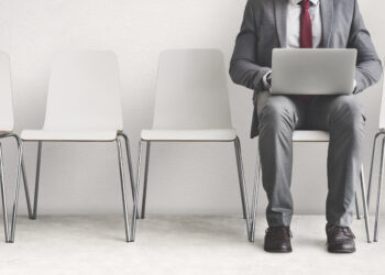 állásinterjúra várakozó öltönyös férifi laptoppal