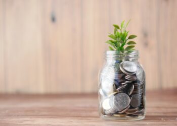 aprópénzzel teli üvegből kinövő növény a növekedést szimbolizálva